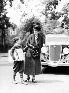 h-armstrong-roberts-newsboy-with-stack-of-papers-under-arms-helping-elderly-woman-with-cane-cross-street